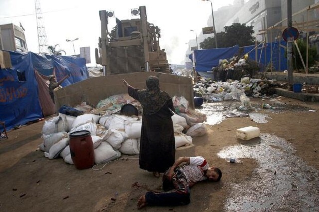 An Egyptian woman stands between a bulldozer and an injured protester bleeding on the ground - Photo - Mohammed Abdel Moneim - AFP - Getty Images